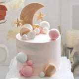 white and pink faux balls used on a light pink shade cake with  a moon and star topper