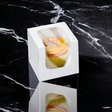 single cupcake box with a beautiful L-shaped window in front, designed to make gifting a breeze. The photograph features the box in its sleek white design, which complements any occasion. The window protects the cupcake while showcasing it, adding a touch of elegance to any gift. Order now for an easy and stress-free gifting experience.