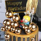 Gold faux balls in use multiple sizes on a black coloured cake with a black and gold topper